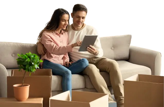 a man and woman sitting on a couch looking at a tablet